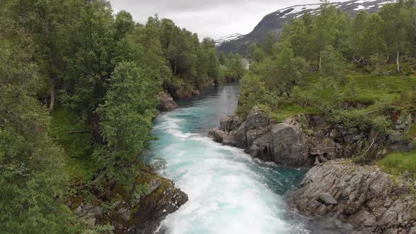Beautiful river cascading down mountainside, aerial dolly view downstream alt