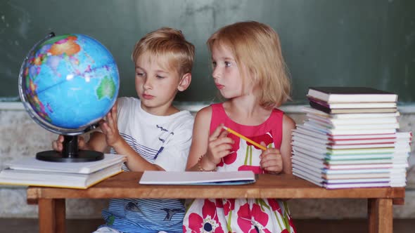 Brother and Sister Study at Home with a World Globe alt
