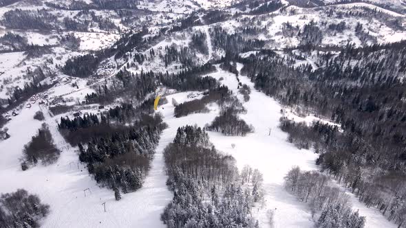 Skier Paragliding Above Ski Resort alt