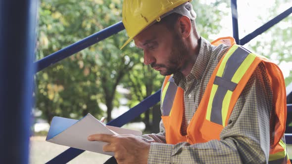 Building Maintenance Technician At Work Writing in His Notebook alt