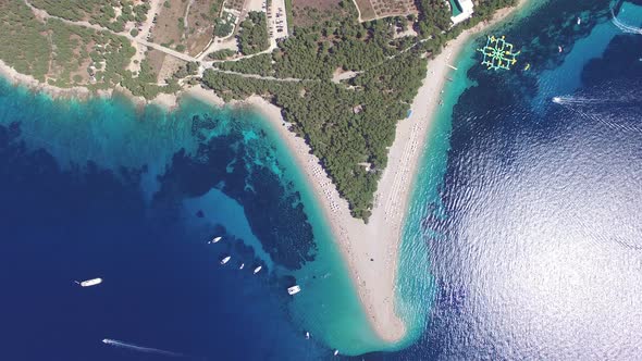 Motorboats passing the sandy beach Zlatni rat on the island of Brac, Croatia alt