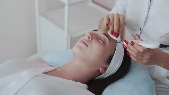Professional Cosmetologist Woman Doing Ultrasonic Face Cleaning to Patient alt