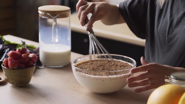 Woman Adds Cocoa Powder From Jar Into Bowl with Milk