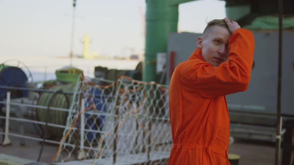 Young Worker in Orange Uniform Walking Through the Harbour By the Sea During His Break alt