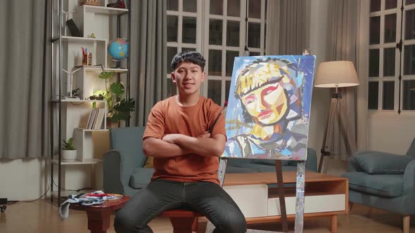 Asian Artist Boy Holding Paintbrush Wipe The Sweat Before Crossing His Arms And Smiling To Camera alt