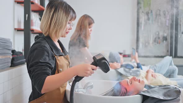 Caucasian young woman lying down and close eye on salon washing bed getting hair washed in salon. alt
