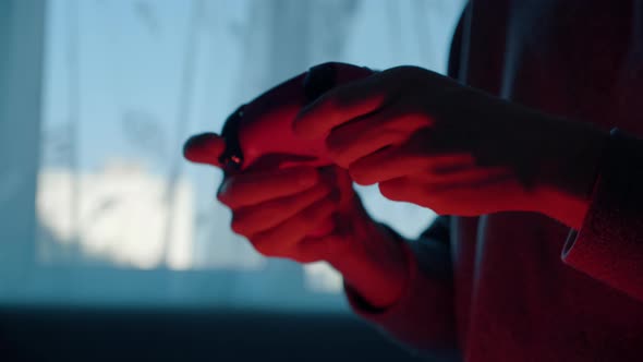 Male Hands Playing Video Game on Gamepad in Dark Red Room Pressing Buttons alt