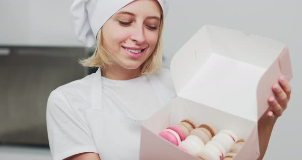 Girl Confectioner In White Hat And Apron Holding Box With Tasty Colorful alt
