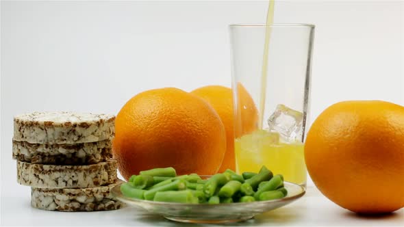Orange Juice Is Poured Into A Glass, Three Oranges, Bread Rolls And Beans For A Healthy Diet