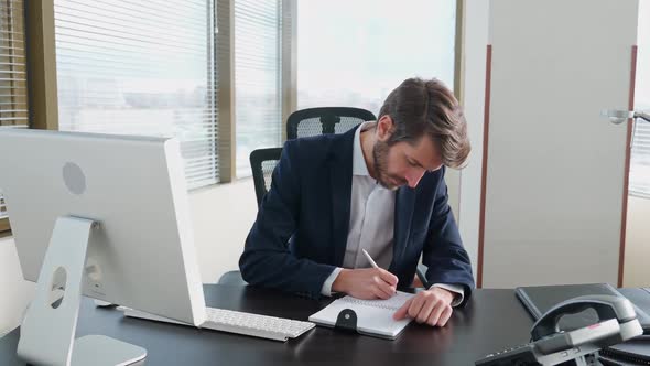 Focused Businessman Working at a PC Sitting at Work Desk Manager Writes the Information in a alt