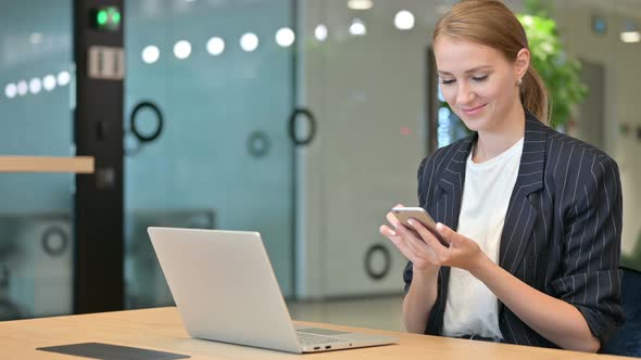 Professional Businesswoman with Laptop Using Smartphone in Office  alt
