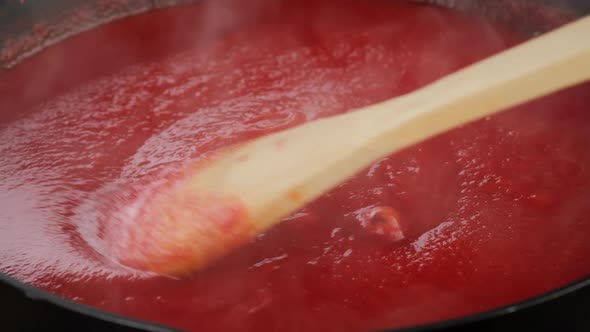 Stir tomato sauce with wooden spoon. 4K UHD video alt