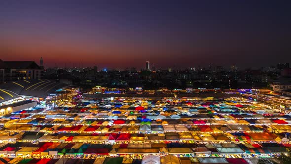 day to night time lapse of Train Night Market Ratchada (Talad Rot Fai) at night in Bangkok, Thailand