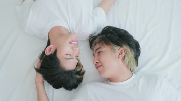 Attractive LGBTQ couple in pajamas, feel happy after wake up in morning and touch cheek of boyfriend alt