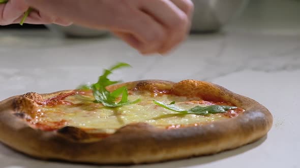 Homemade pizza. baker decorates pizza from oven with fragrant basil