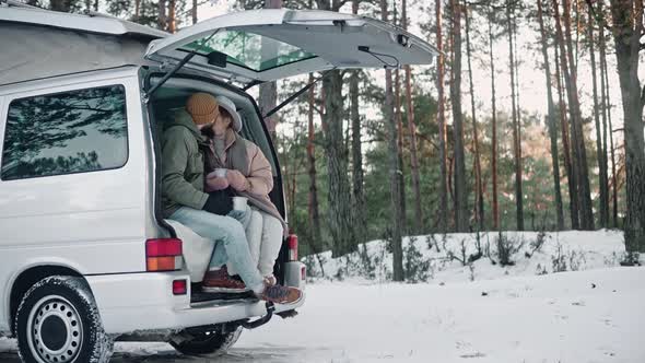 Romantic Couple Sitting at the Back of a Van in the Woods on a Sunny Winter Day