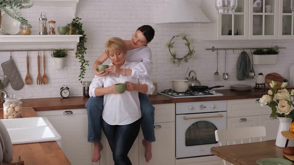 Smiling Elderly and Young Women Enjoying Time at Home, Drinking Tea Together.