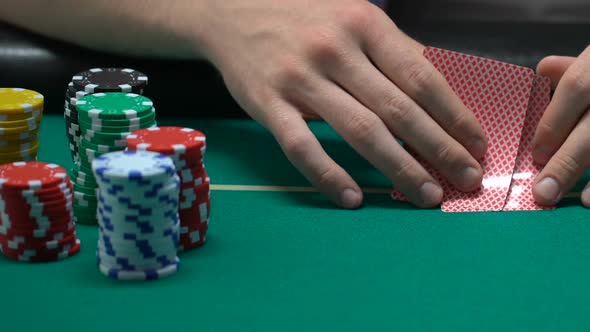 People Playing Poker, Man Looking at His Cards and Pushing Chips, All-In alt