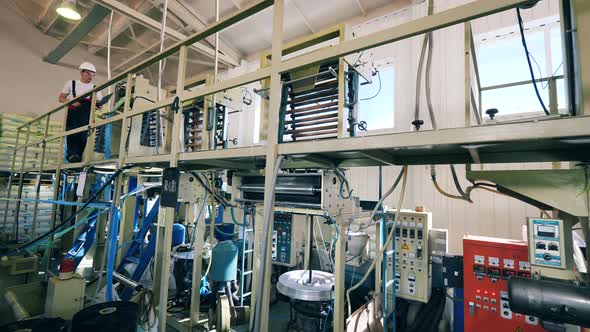 Male Technician Is Walking Along the Plastic Factory and Inspecting It alt