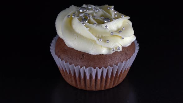 Vanilla cupcake with berry filling and honey cream cheese on black background alt