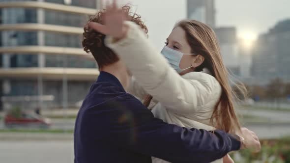 Teenagers in Medical Masks a Guy and Girls Hug Against the Background of City Buildings