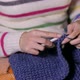 A Young Girl Knits a Scarf Snood Sitting on the Couch Covered with a Blanket - VideoHive Item for Sale