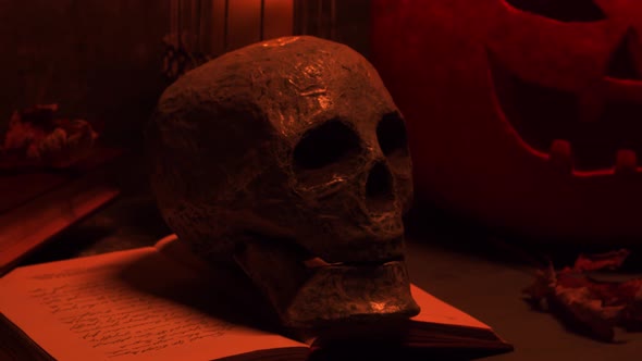 Scary laughing pumpkin and an old skull over the frightening gothic background. alt