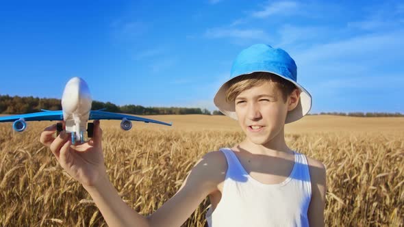Portrait of a Boy with a Toy Plane in a Golden Wheat Field