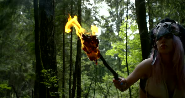 Savage Woman Is Looking Around and Hearing in Forest in Daytime, Burning Torch alt