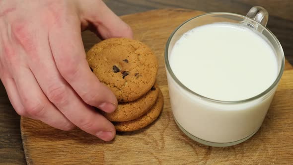 Hand putting a cookie beside glass of milk. Close up. HD