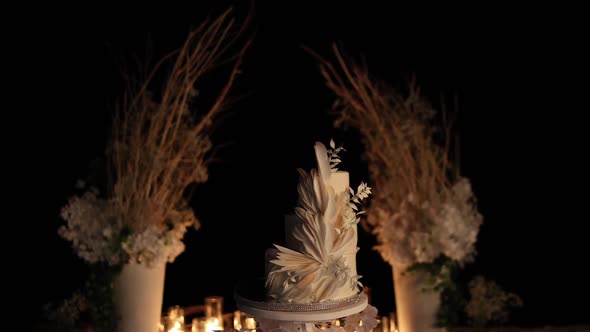 beautiful wedding cake near the wedding arch in the evening