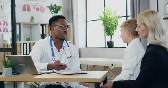 Mother with Handsome Son Visiting Local Doctor at Private clinic alt