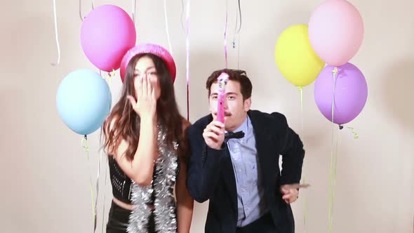 Funny couple dancing and blowing party horns alt