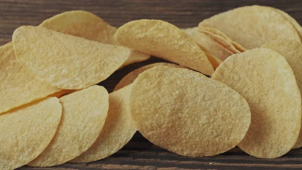 Potato chips on a wooden background. Salty crisps scattered on a table.