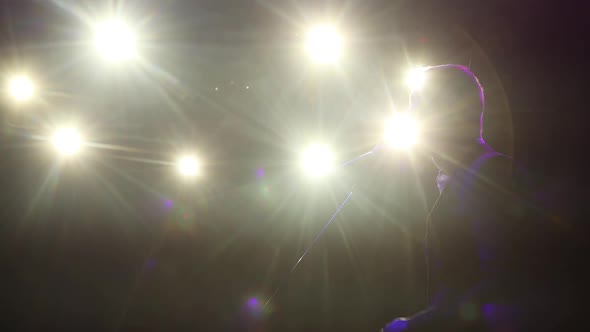 Silhouette of Man Comedian Speaking Micropphone Standing on Stage in Spotlights.