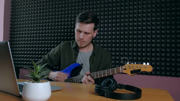 Male Learning Play Guitar at Home Using Online Lessons alt