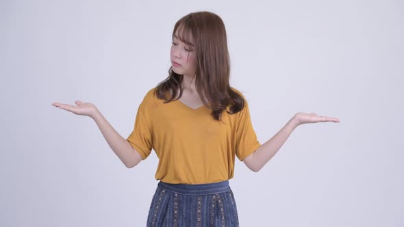 Happy Young Asian Woman Comparing Something alt
