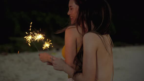 beautiful asian woman and her friends are having fun playing sparklers on the beach during Twilight