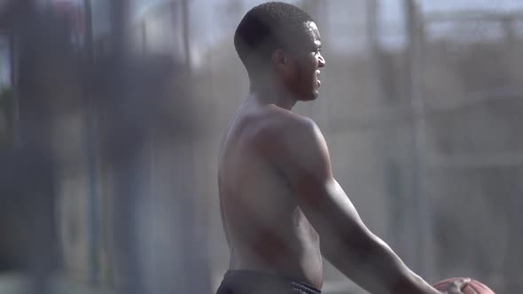 A young man playing basketball on a rainy day. alt