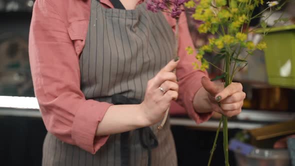 Young Woman Florist Is Making Bouquet of Fresh Wildflowers While Working in Store.