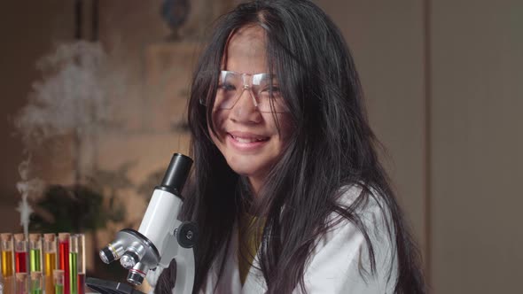 Young Scientist Girl With Dirty Face Looking At Microscope And Smiles To Camera In Laboratory alt