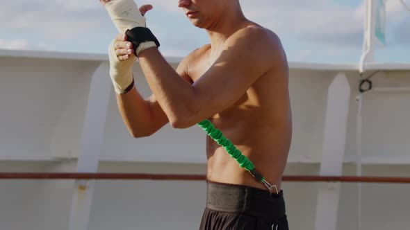Young Boxer Starts Box Workout with Resistance Band Training Strap System Outdoors
