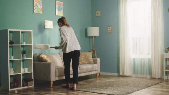 Pretty Woman in White Sweater Wipes Dust From Furniture alt