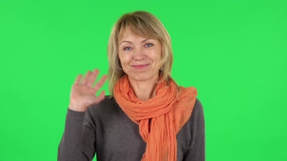 Portrait of Middle Aged Blonde Woman Is Waving Hand and Showing Gesture Come Here alt