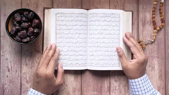 Muslim Man Hand Turning Pages of Holly Book of Quran Top View alt