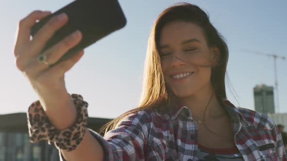 Portrait of smiling caucasian woman taking selfie at a skatepark alt