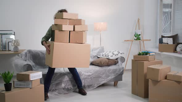 Man with Cardboard Boxes Loses His Balance and Slowly Falls on Sofa Covered with Oilcloth Problems alt