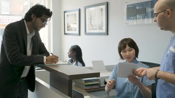 Patient filling out questionnaire and getting documents from dentist alt
