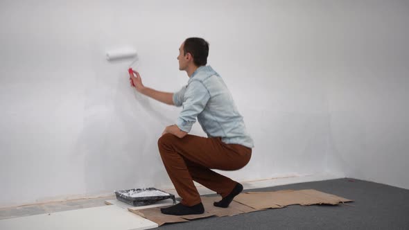 Male Decorator Painting a Wall with White Color