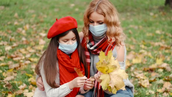 Mother And Her Daughter Playing With Fallling Leaves In Autumn Park alt